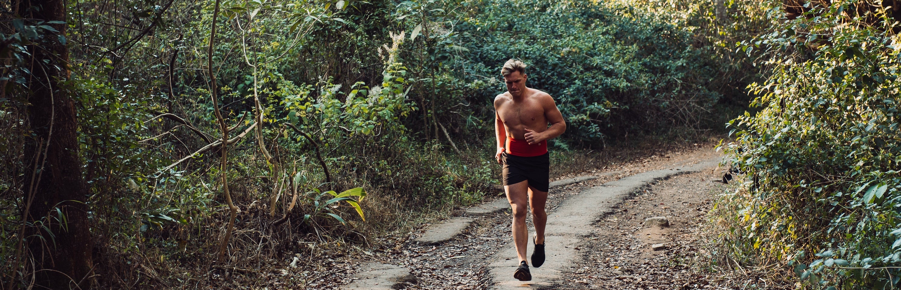 Man running whilst wearing a red StashBandz running belt
